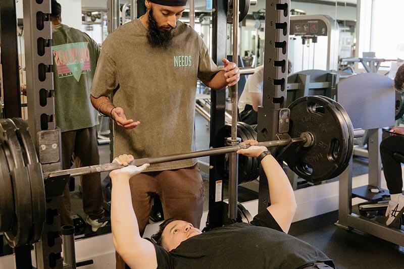 Needs Gym helping client benchpress